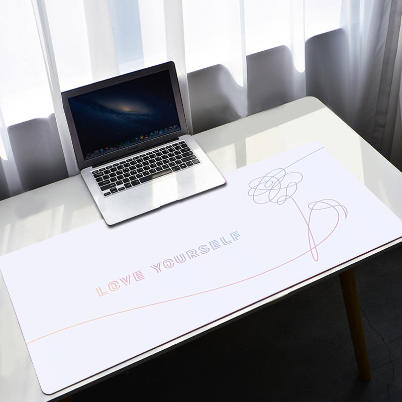 Laptop on a desk with a large mouse pad featuring 'LOVE YOURSELF' text.