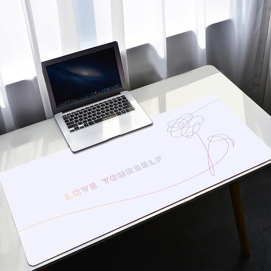 Laptop on a desk with a large mouse pad featuring 'LOVE YOURSELF' text.