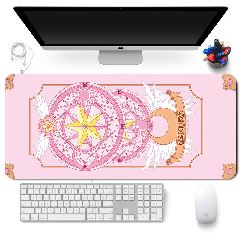 Pink desk mat with anime design on a desk setup with a computer monitor, keyboard, and mouse.